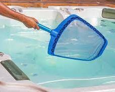 Service team member holding net cleaning hot tub
